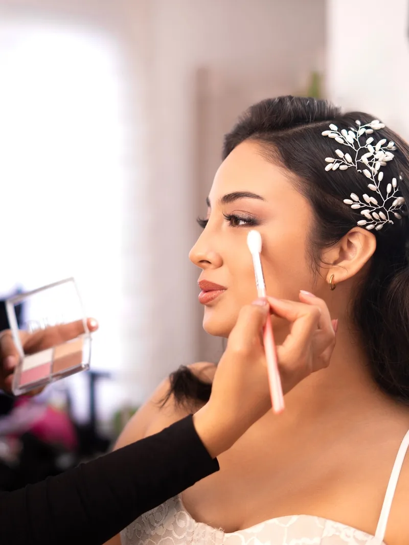 Liz aplicando maquillaje a una novia con tocado floral